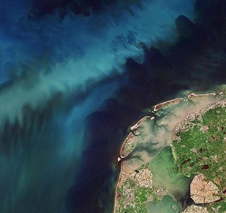 Satellittbilde av Nederland viser både fargerike tulipanmarker i full blomst og blågrønne virvler av planteplankton i Nordsjøen – et unikt “dobbelt blomstringsfenomen” sett fra rommet. (contains modified Copernicus Sentinel data (2025), processed by ESA)
